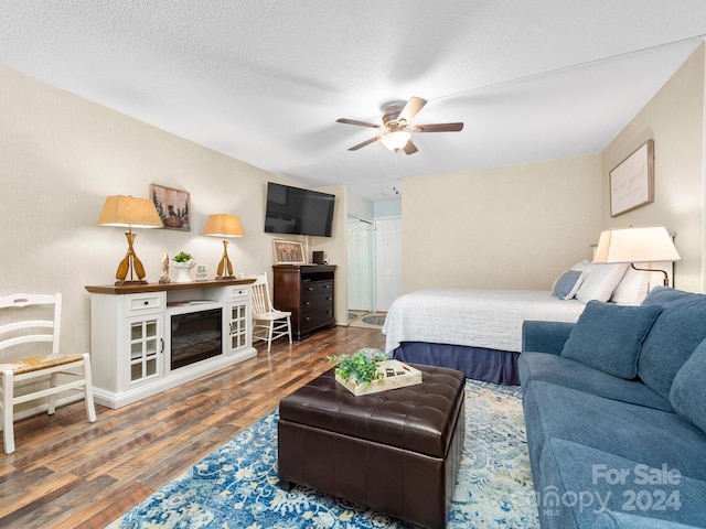 bedroom featuring ceiling fan, dark hardwood / wood-style flooring, and a textured ceiling