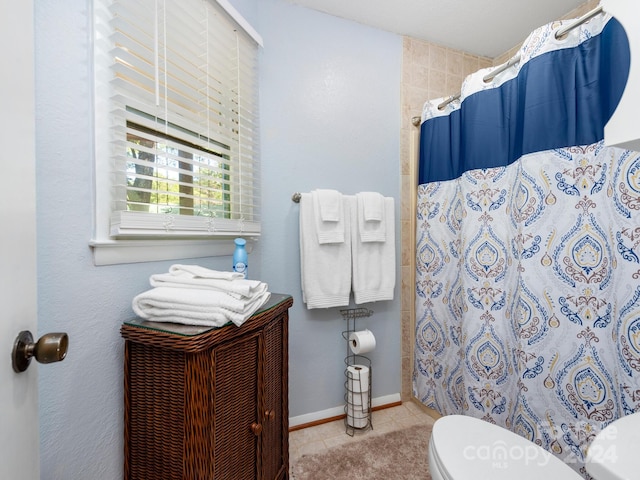 bathroom featuring tile patterned flooring, toilet, and walk in shower