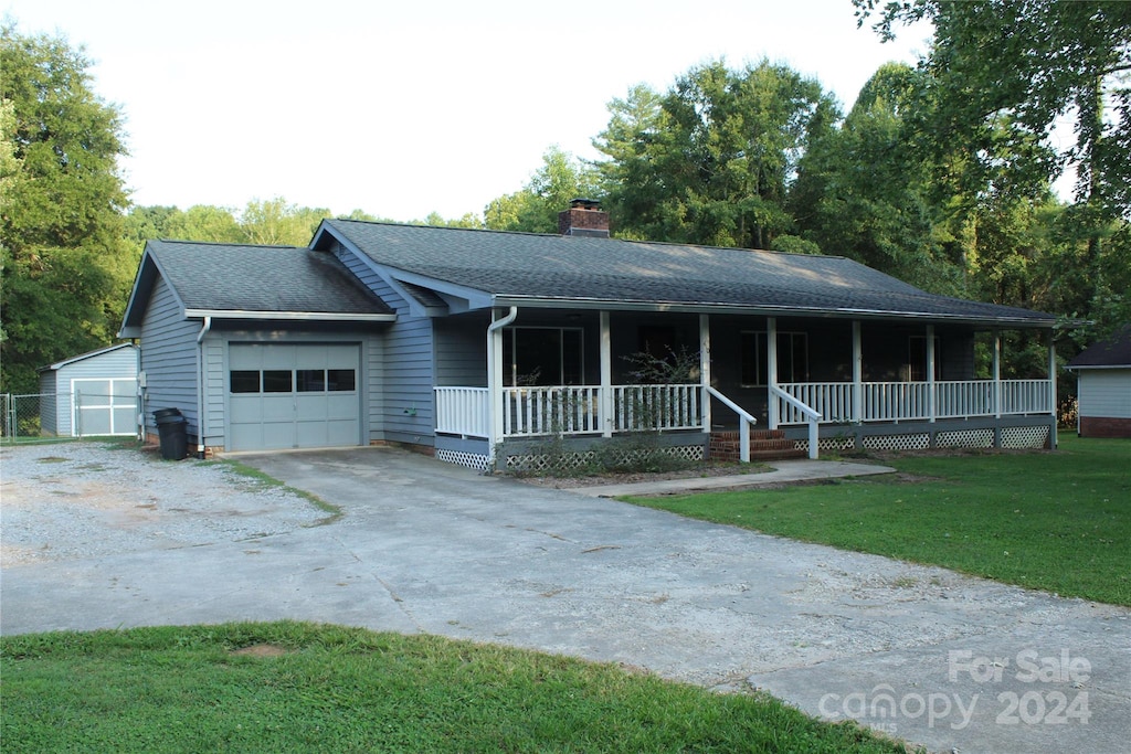 ranch-style home with a garage, covered porch, and a front lawn