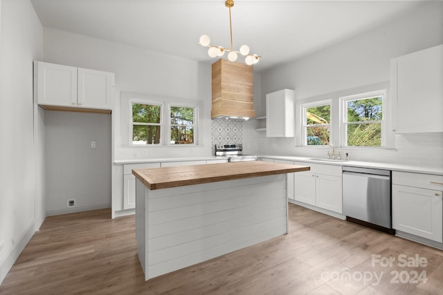 kitchen featuring light wood-type flooring, stainless steel appliances, butcher block counters, and a healthy amount of sunlight