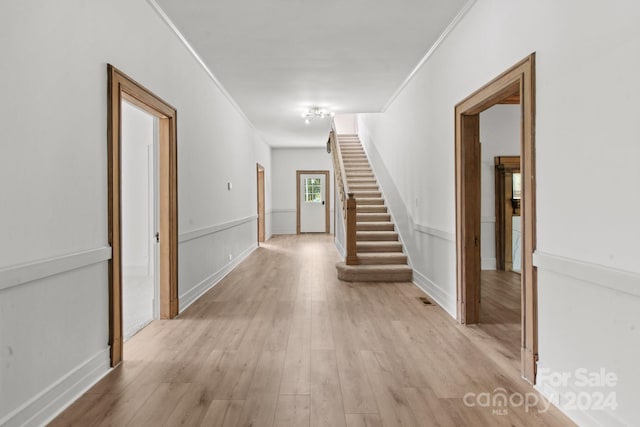 corridor featuring light wood-type flooring and crown molding