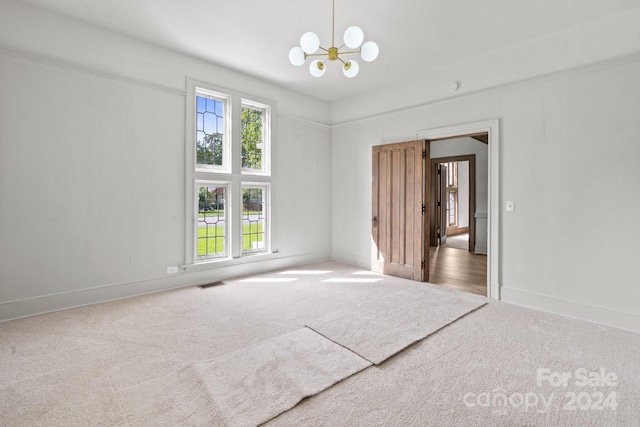 carpeted empty room featuring a chandelier