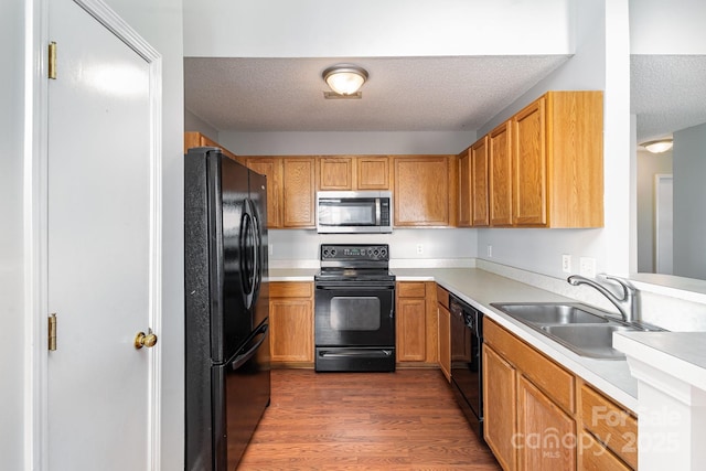 kitchen with sink, dark wood-type flooring, a textured ceiling, and black appliances