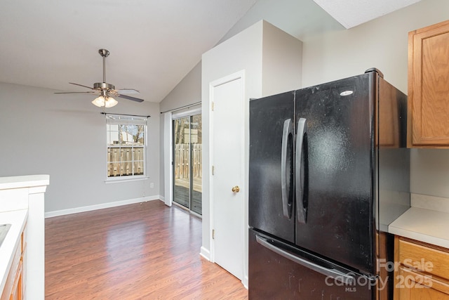 kitchen featuring lofted ceiling, hardwood / wood-style flooring, ceiling fan, and black fridge