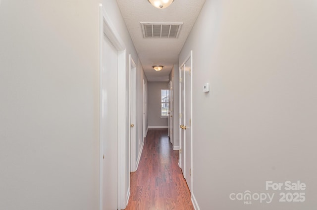 corridor with dark wood-type flooring and a textured ceiling