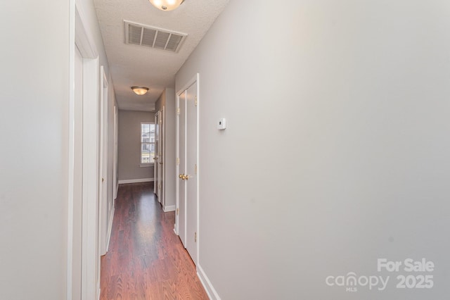 corridor with dark hardwood / wood-style flooring and a textured ceiling