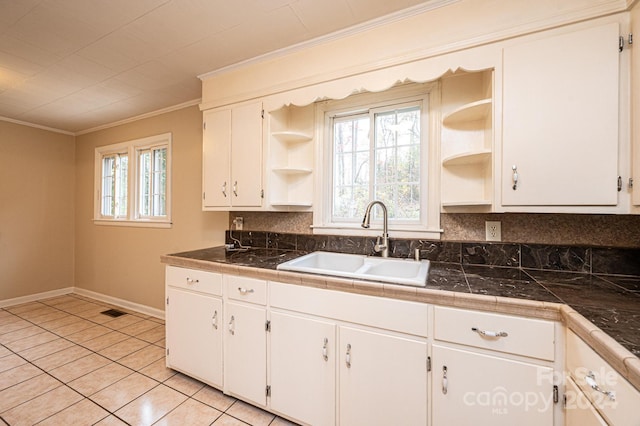 kitchen featuring backsplash, white cabinets, crown molding, sink, and light tile patterned flooring