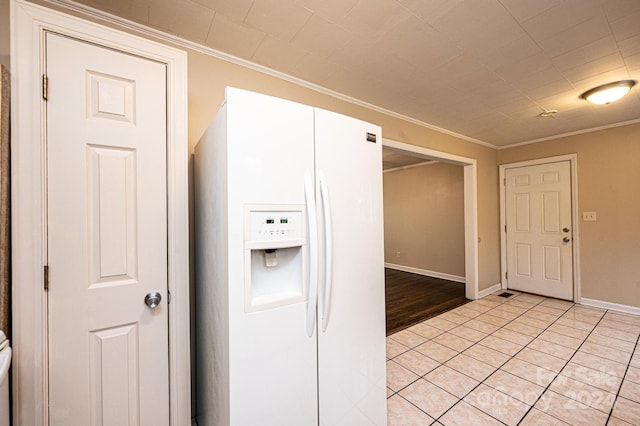 kitchen with white cabinets, crown molding, light tile patterned floors, and white refrigerator with ice dispenser