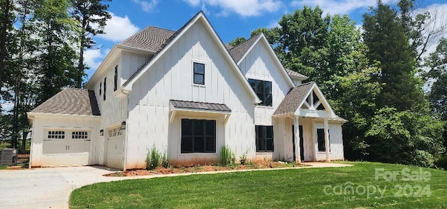 modern inspired farmhouse with a garage, a front lawn, and central air condition unit