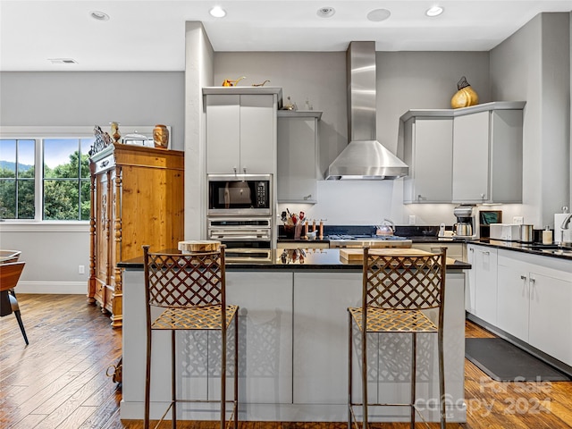 22 Foxbridge Way, Arden, NC 28704 - kitchen with wall chimney range hood, appliances with stainless steel finishes, dark countertops, a kitchen bar, and recessed lighting