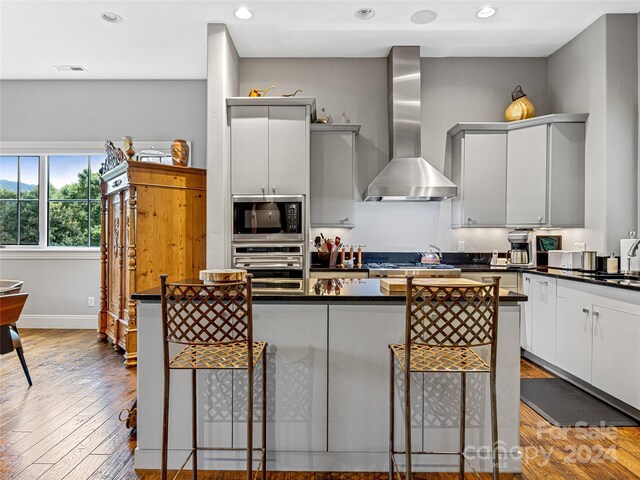 22 Foxbridge Way, Arden, NC 28704 - kitchen with wall chimney range hood, appliances with stainless steel finishes, dark countertops, a kitchen bar, and recessed lighting