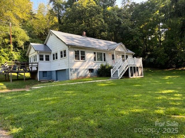 single story home with a front yard, metal roof, a deck, and stairs