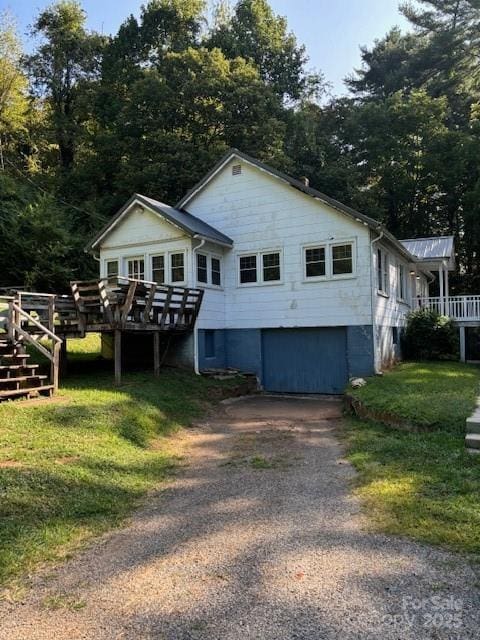 view of front facade with driveway, a front yard, and a wooden deck