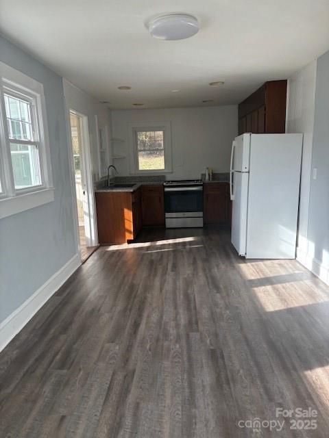 kitchen featuring stainless steel electric range oven, dark wood-type flooring, a sink, and freestanding refrigerator