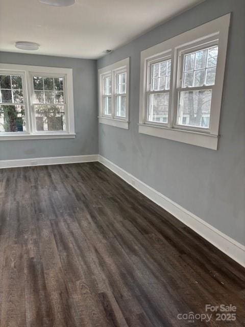 empty room featuring baseboards and dark wood finished floors