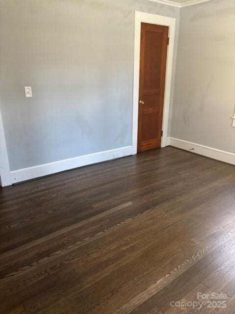 spare room featuring dark wood-type flooring and baseboards