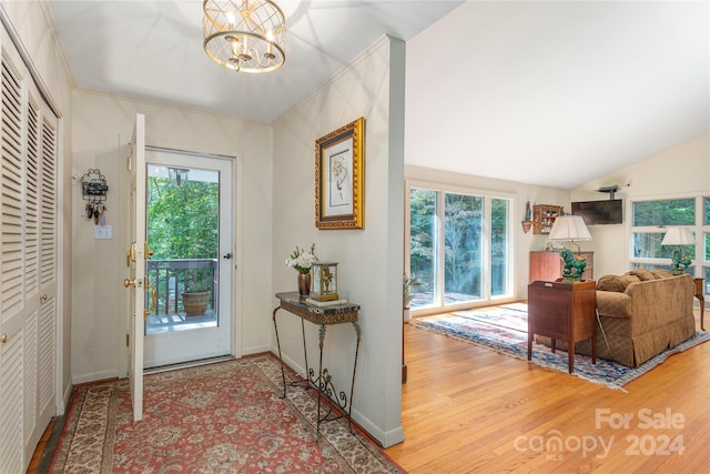 doorway featuring lofted ceiling, hardwood / wood-style floors, and a notable chandelier