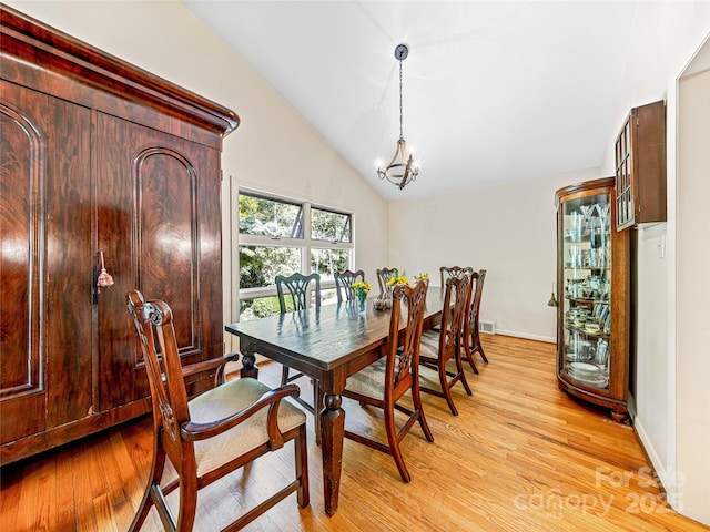 dining room with lofted ceiling, light hardwood / wood-style floors, and a notable chandelier