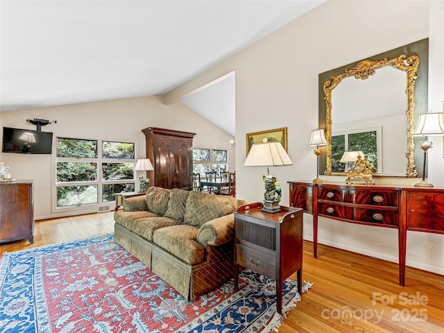 living room with light hardwood / wood-style flooring and lofted ceiling with beams