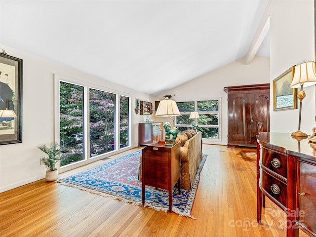 living room featuring vaulted ceiling with beams, light wood-type flooring, and plenty of natural light