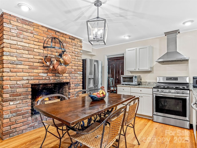 kitchen featuring light stone countertops, wall chimney exhaust hood, stainless steel appliances, and white cabinetry