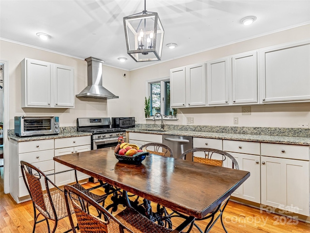 kitchen featuring white cabinets, appliances with stainless steel finishes, wall chimney exhaust hood, sink, and light stone counters