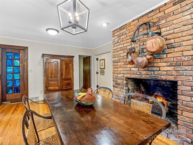 dining room with a fireplace, a chandelier, crown molding, and light hardwood / wood-style floors