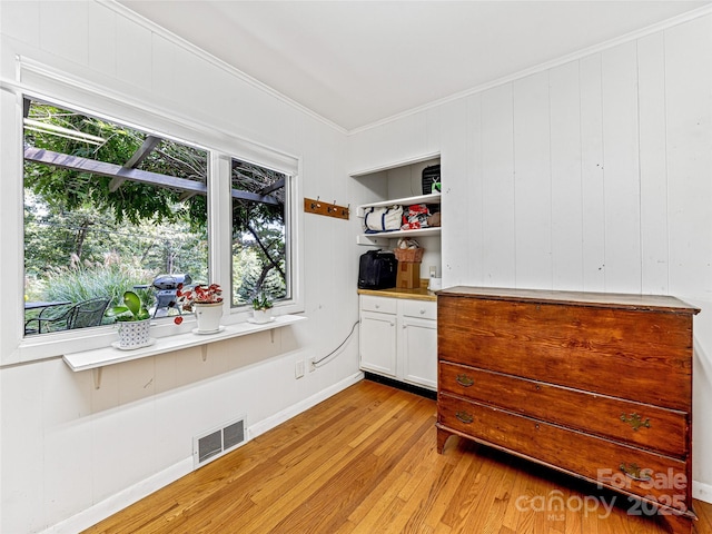 unfurnished bedroom featuring light hardwood / wood-style floors, multiple windows, and ornamental molding