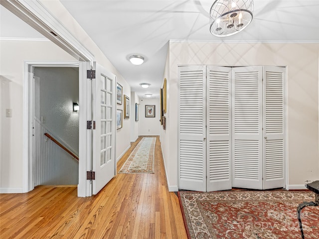 corridor with crown molding, light hardwood / wood-style flooring, and a notable chandelier