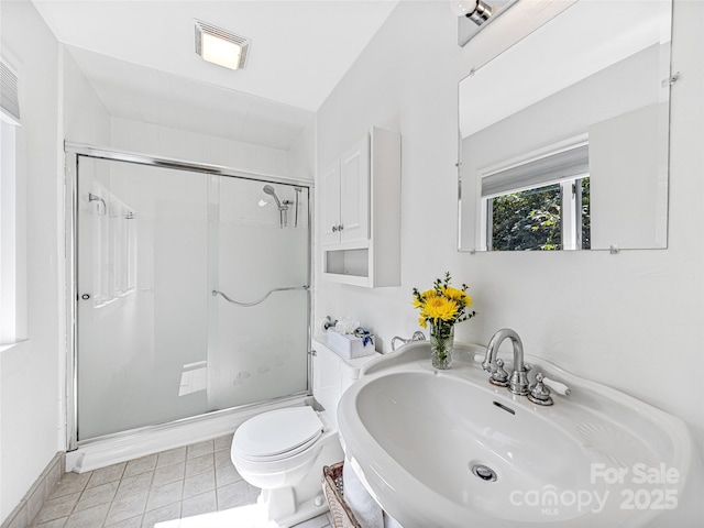 bathroom featuring a shower with shower door, sink, and toilet