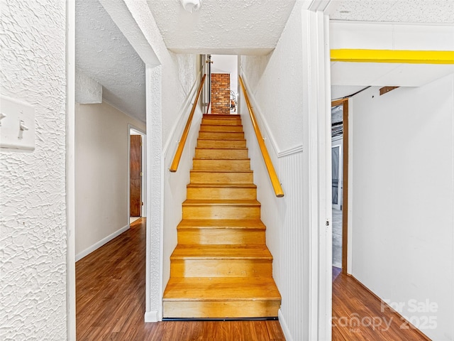 stairway with a textured ceiling and hardwood / wood-style floors