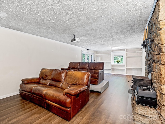 living room featuring built in shelves, dark hardwood / wood-style flooring, and a textured ceiling