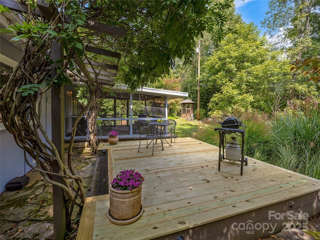 wooden terrace featuring a grill and a sunroom