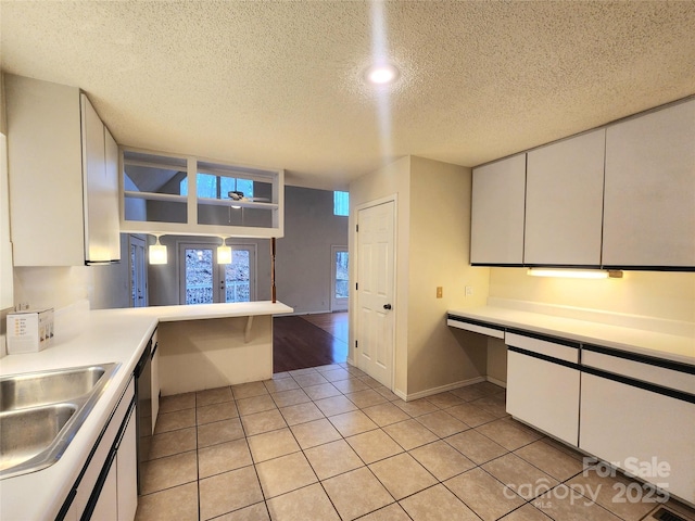 kitchen featuring light tile patterned floors, kitchen peninsula, french doors, and white cabinets