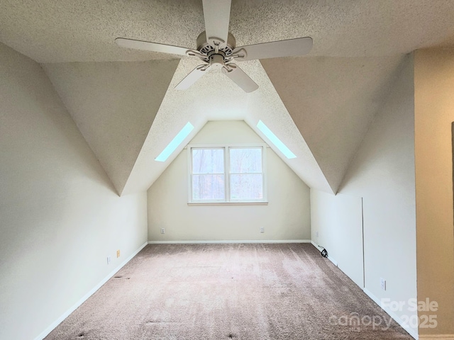 additional living space with lofted ceiling, ceiling fan, light colored carpet, and a textured ceiling