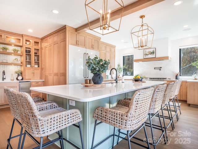 kitchen featuring a kitchen bar, light brown cabinets, a large island, light hardwood / wood-style flooring, and high end refrigerator