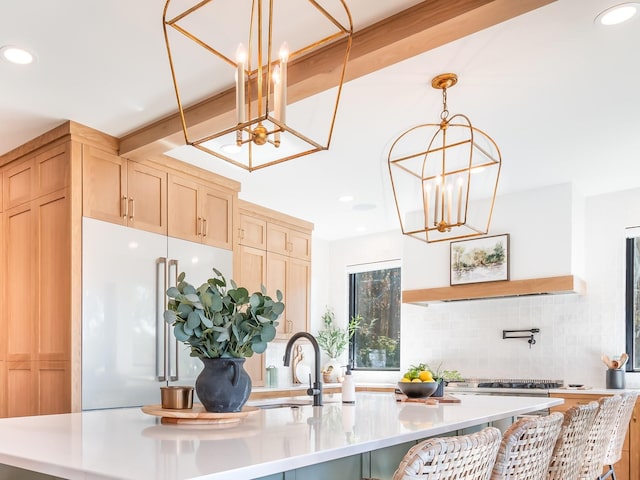 kitchen with a center island with sink, decorative backsplash, high end refrigerator, light brown cabinetry, and sink