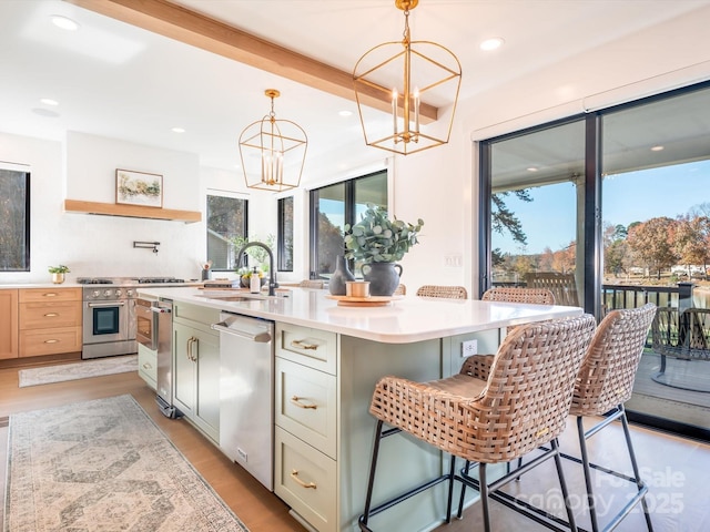 kitchen with a center island with sink, beam ceiling, sink, a kitchen breakfast bar, and stainless steel appliances