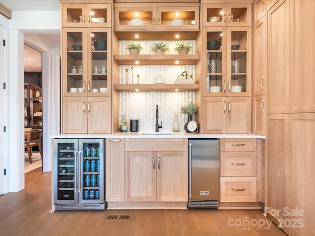 bar featuring sink, beverage cooler, and light brown cabinets