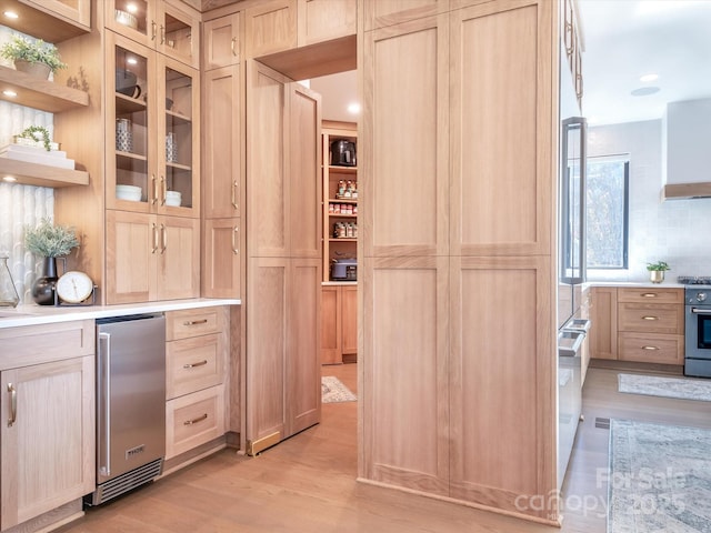 bar featuring light brown cabinetry, light hardwood / wood-style floors, high end stainless steel range, and refrigerator