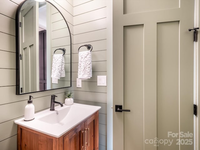 bathroom featuring wooden walls and vanity