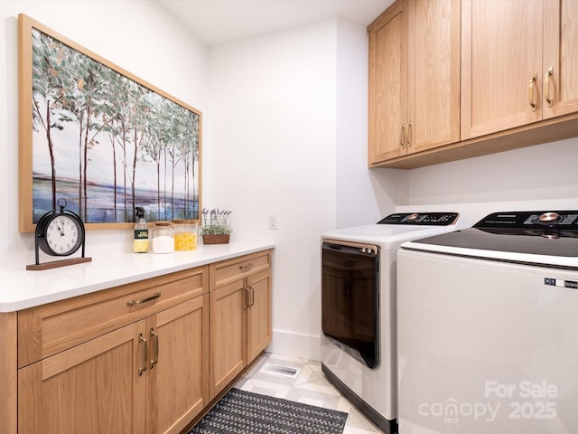 washroom with cabinets, washing machine and dryer, and light tile patterned flooring