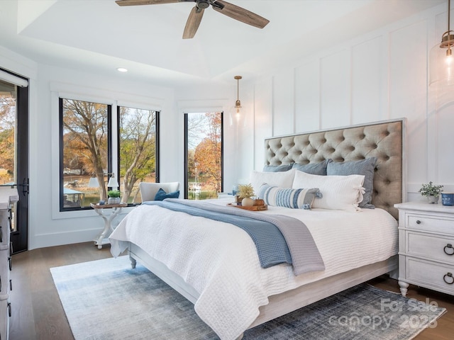 bedroom with ceiling fan, dark hardwood / wood-style floors, and a tray ceiling