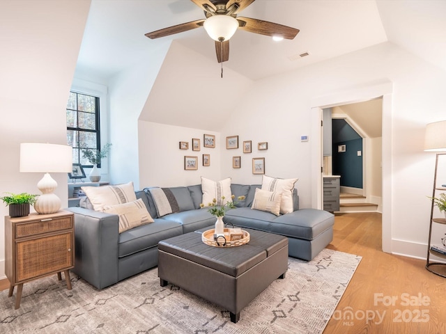 living room featuring ceiling fan, vaulted ceiling, and light wood-type flooring