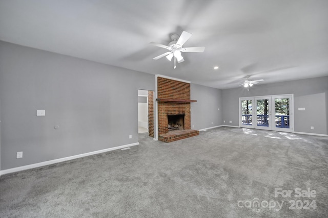 unfurnished living room featuring a brick fireplace, ceiling fan, and carpet flooring