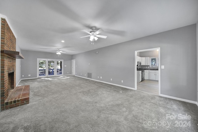 unfurnished living room with ceiling fan, light colored carpet, and a fireplace