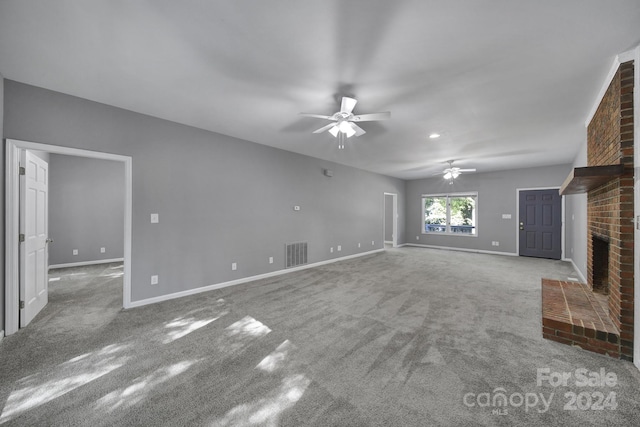 unfurnished living room featuring ceiling fan, light colored carpet, and a brick fireplace