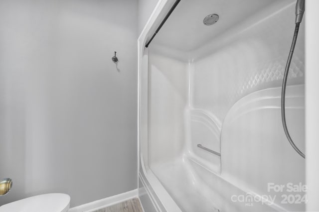 bathroom with walk in shower, toilet, and hardwood / wood-style flooring