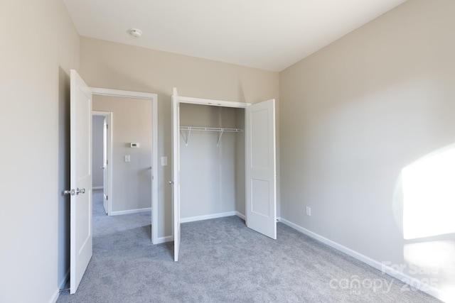 unfurnished bedroom with light carpet and a closet