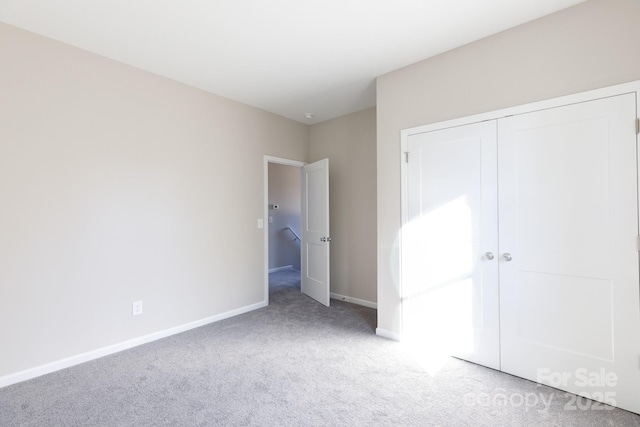 unfurnished bedroom with light colored carpet and a closet